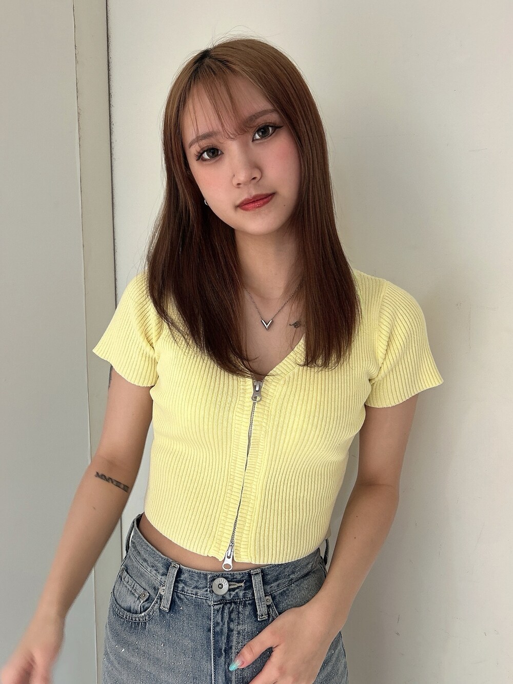 イエロー系のニット/セーター、ブルー系のデニムパンツ、ホワイト系のパンプスを着用したレディースの春コーディネートの4枚目の写真