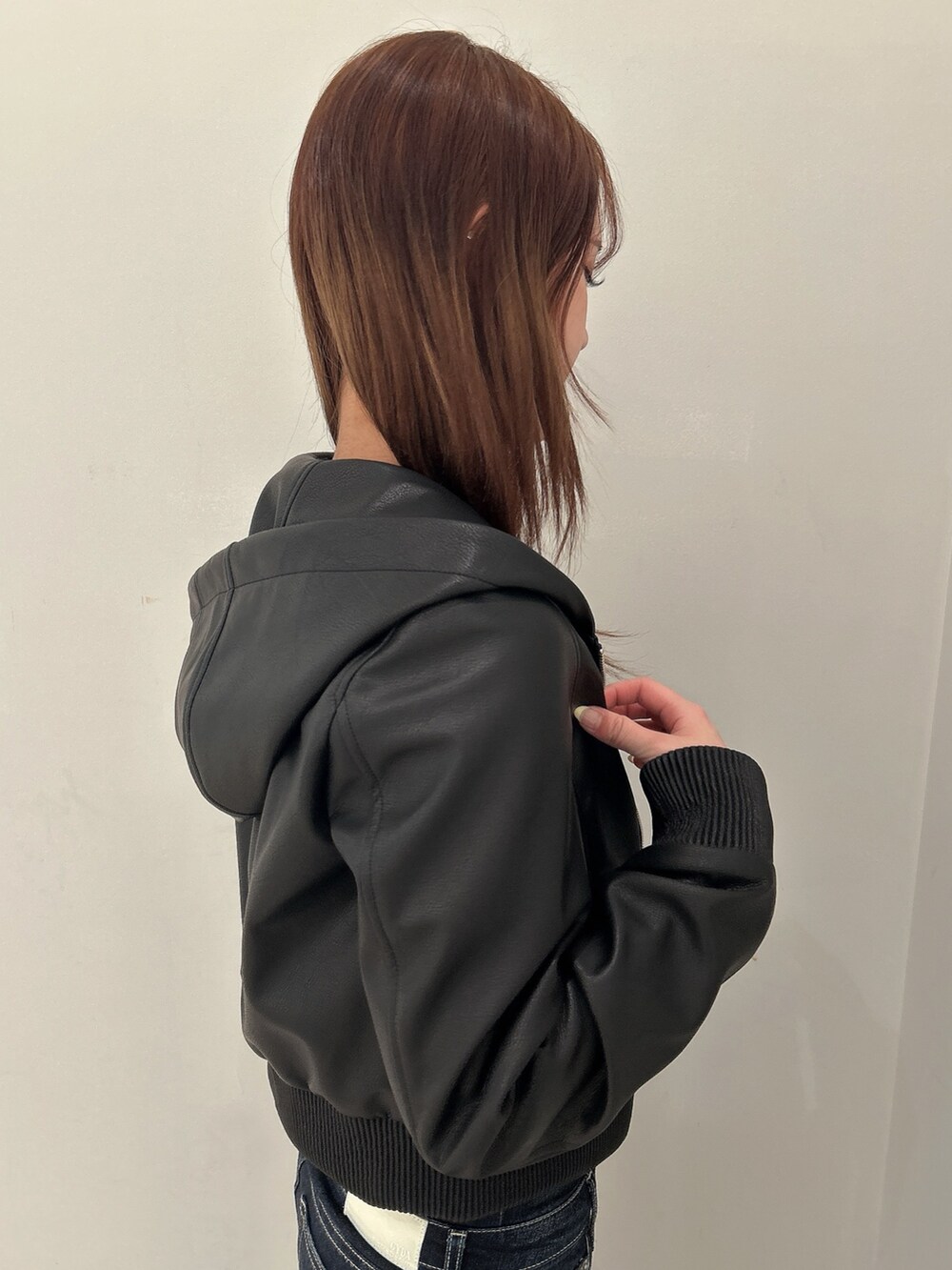 ブラック系のニット/セーター、ブラック系のブルゾン、ブルー系のデニムパンツを着用したレディースの春コーディネートの6枚目の写真