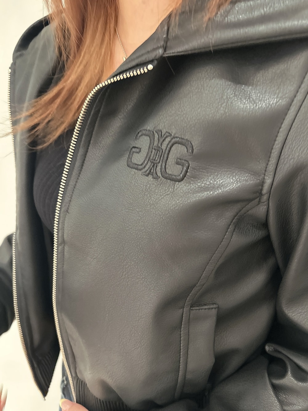 ブラック系のニット/セーター、ブラック系のブルゾン、ブルー系のデニムパンツを着用したレディースの春コーディネートの7枚目の写真