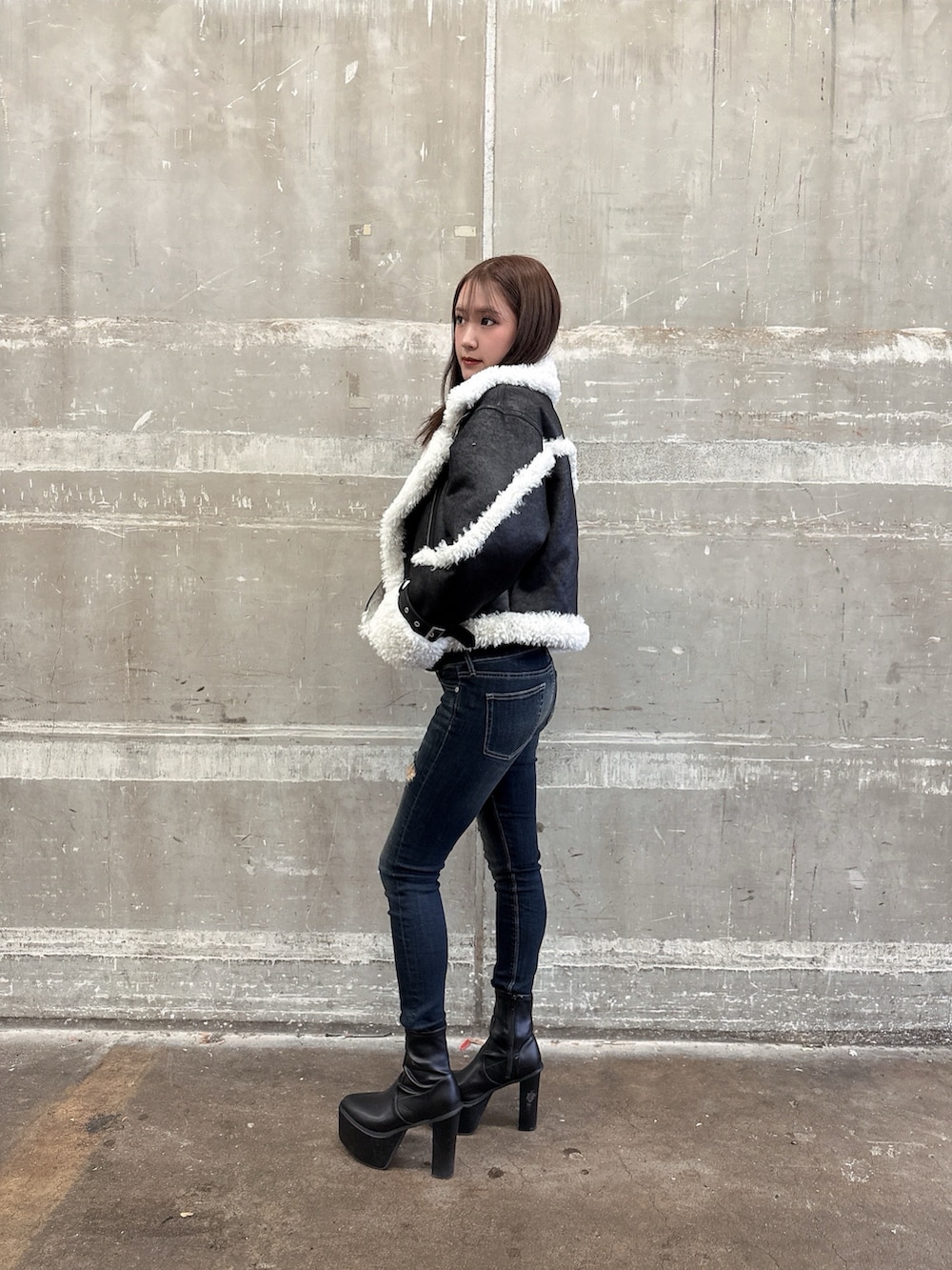 ブラック系のムートンコート、ブラック系のスウェット、ブルー系のデニムパンツを着用したレディースの秋コーディネートの2枚目の写真