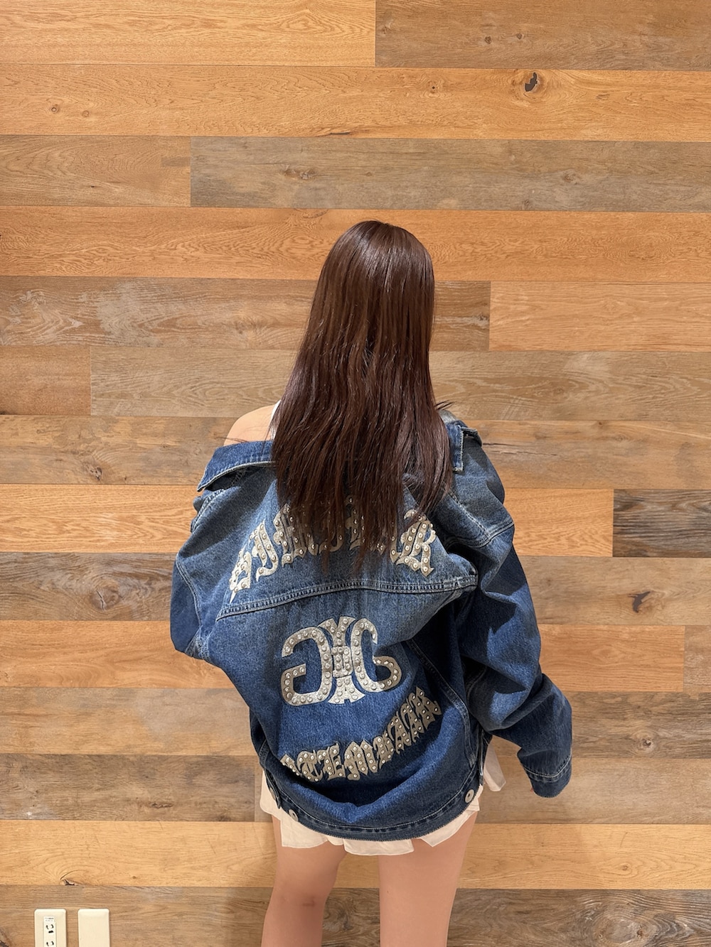 ブルー系のデニムジャケット、ブラック系のTシャツ/カットソー、ホワイト系のスカートを着用したレディースの春コーディネートの6枚目の写真