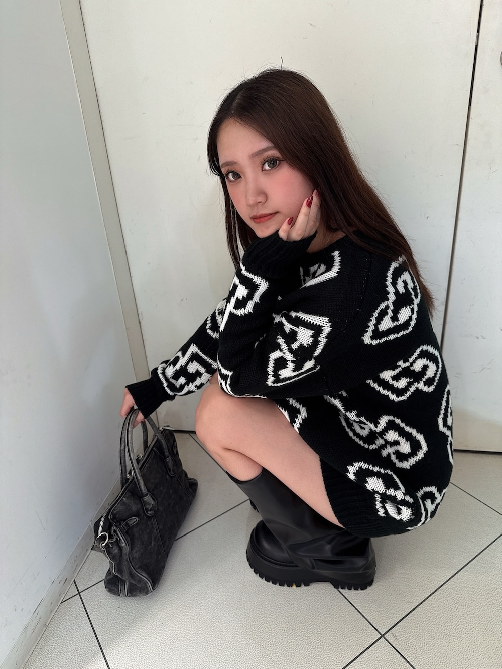 ブラック系のニット/セーター、ブラック系のスカート、ブラック系のブーツを着用したレディースの秋コーディネートの7枚目の写真