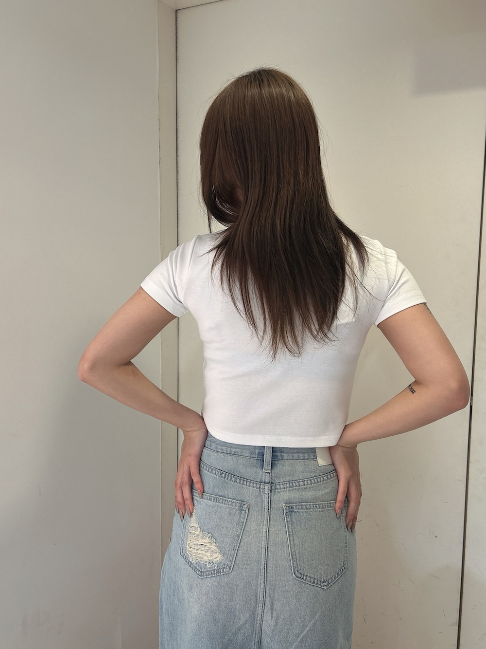 ホワイト系のTシャツ/カットソー、ブルー系のデニムスカート、ホワイト系のサンダルを着用したレディースの春コーディネートの6枚目の写真