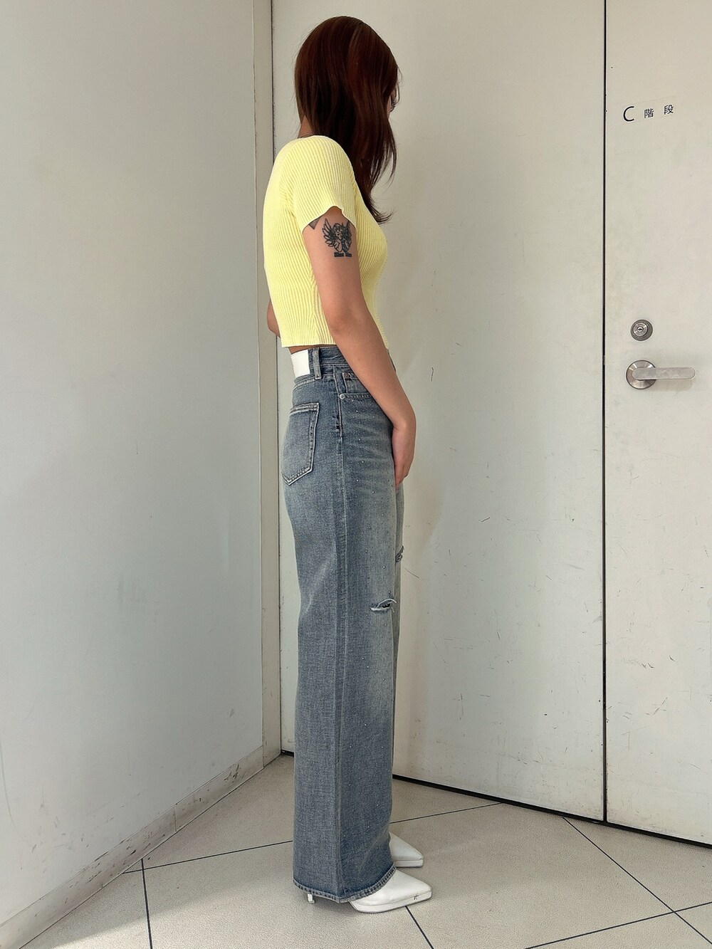 イエロー系のニット/セーター、ブルー系のデニムパンツ、ホワイト系のパンプスを着用したレディースの春コーディネートの2枚目の写真