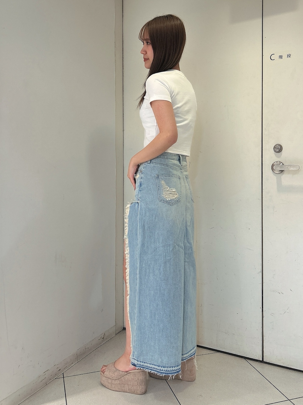 ホワイト系のTシャツ/カットソー、ブルー系のデニムスカート、ホワイト系のサンダルを着用したレディースの春コーディネートの2枚目の写真