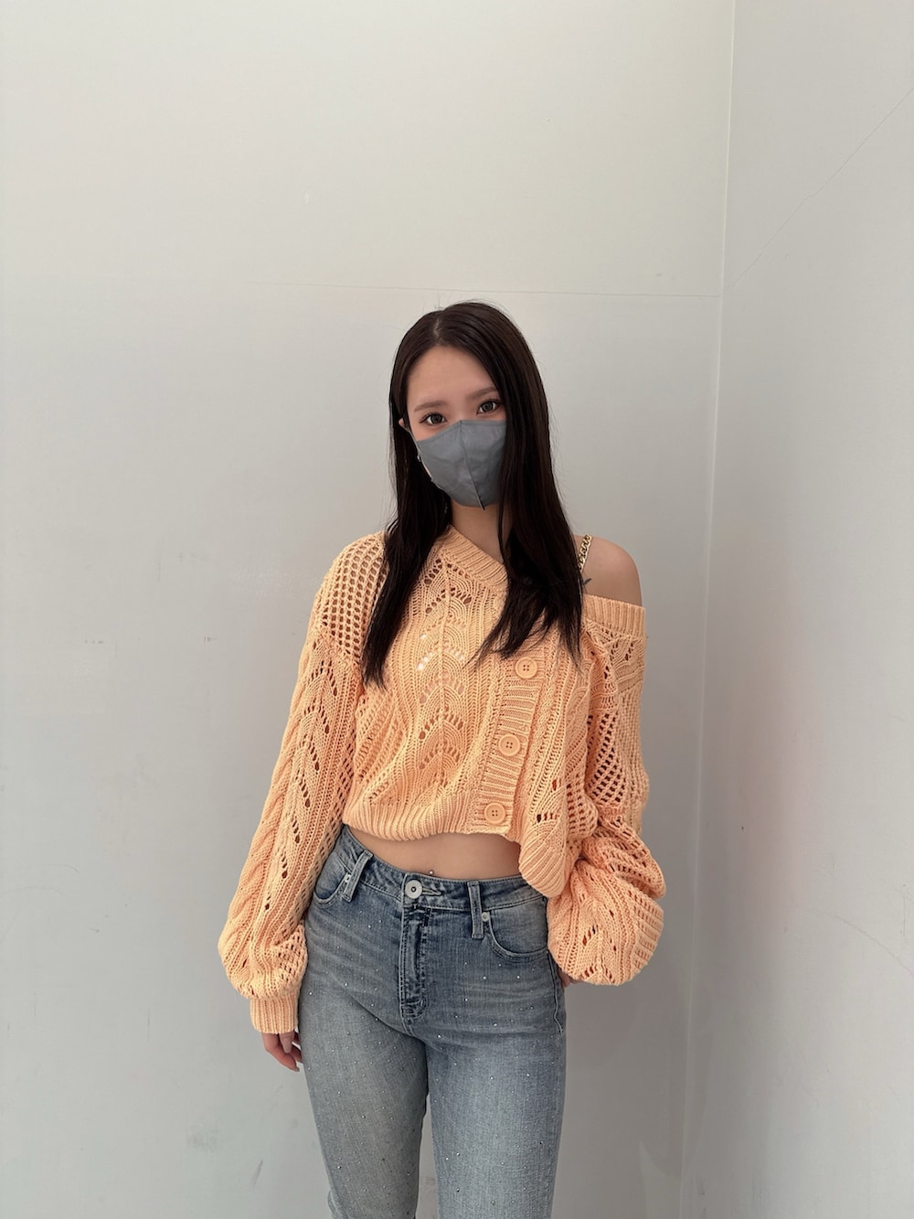 オレンジ系のニット/セーター、ホワイト系のキャミソール、ブルー系のデニムパンツを着用したレディースの春コーディネートの4枚目の写真