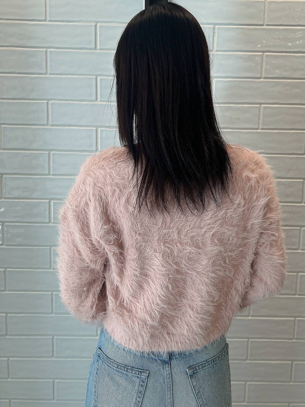 ピンク系のニット/セーター、ブルー系のデニムパンツ、ベージュ系のブーツを着用したレディースの冬コーディネートの5枚目の写真