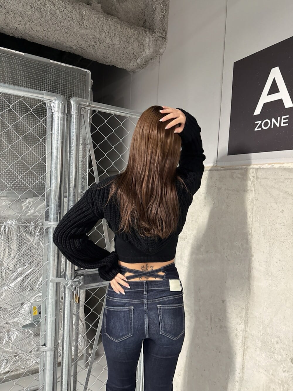 ブラック系のブーツ、ブラック系のニット/セーター、ブルー系のデニムパンツを着用したレディースの冬コーディネートの6枚目の写真