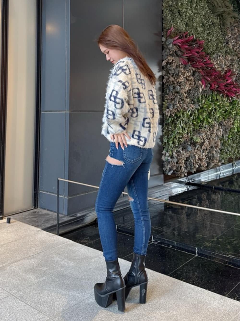 ブラック系のブーツ、ホワイト系のニット/セーター、ブルー系のデニムパンツを着用したレディースの冬コーディネートの2枚目の写真