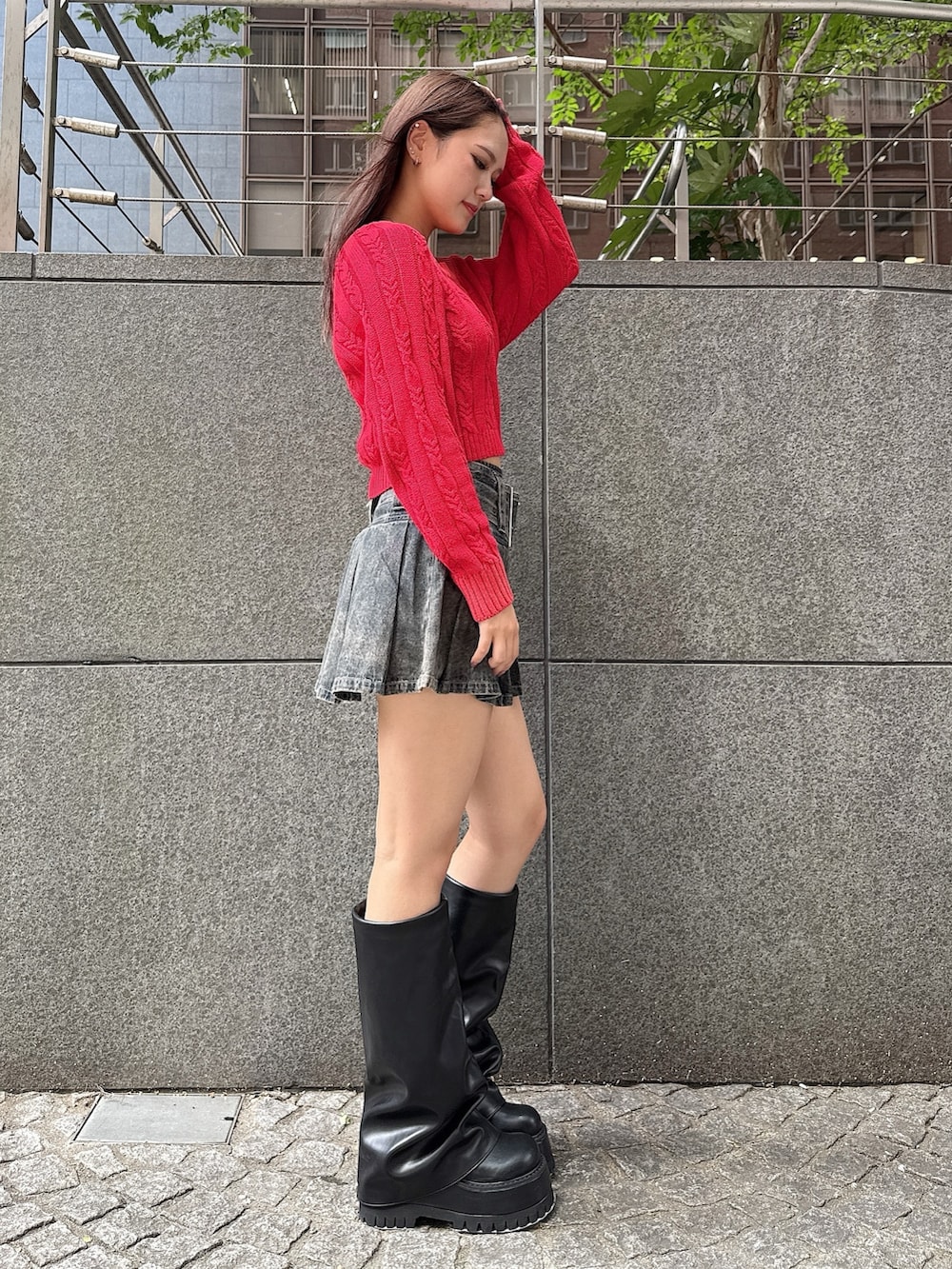 レッド系のニット/セーター、ブルー系のデニムスカート、ブラック系のブーツを着用したレディースの秋コーディネートの2枚目の写真