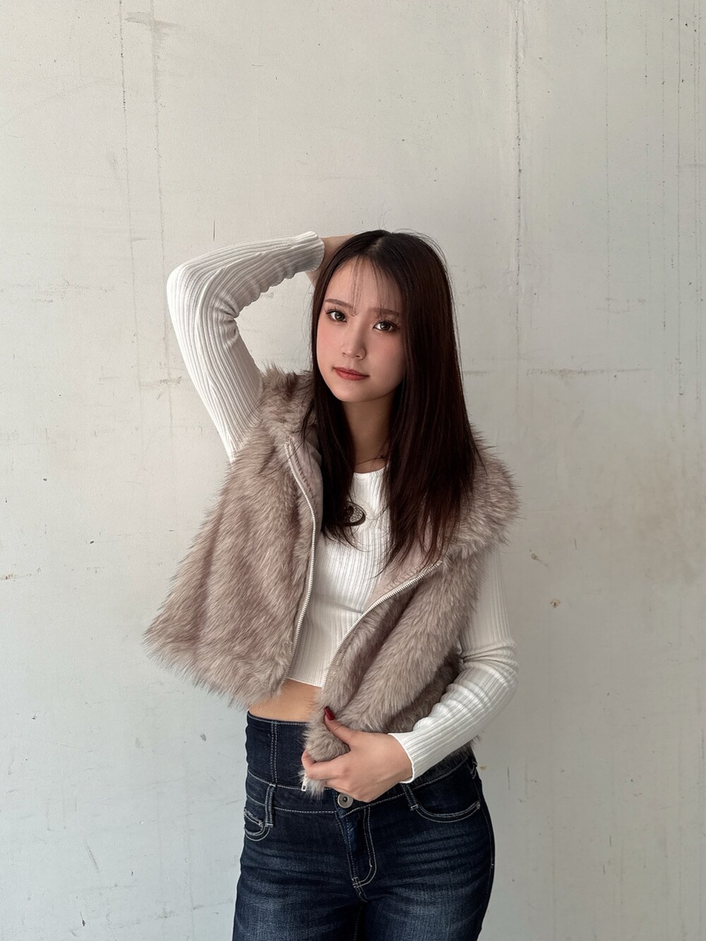 ホワイト系のニット/セーター、ホワイト系のベスト、ブルー系のデニムパンツを着用したレディースの秋コーディネートの4枚目の写真