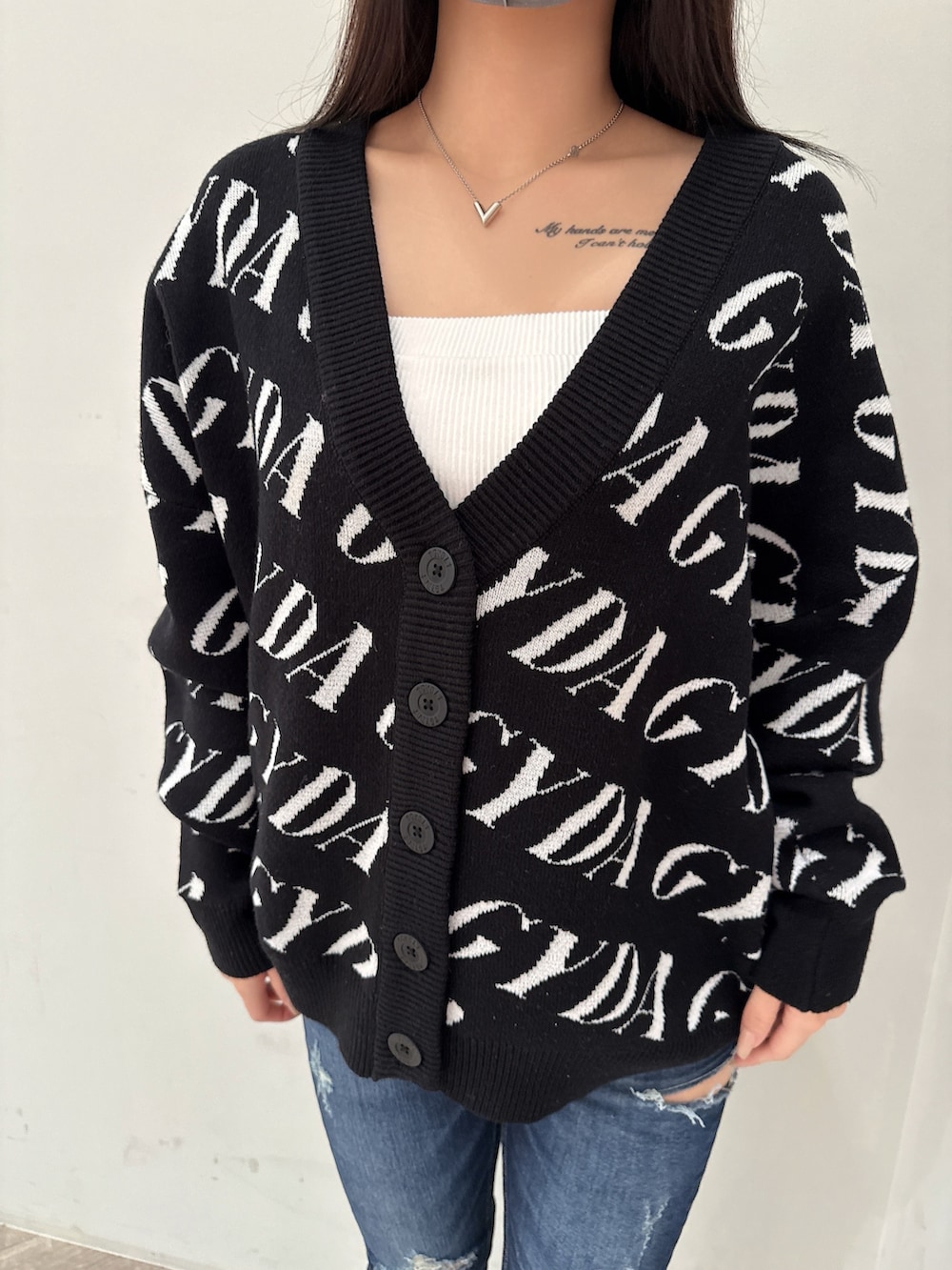 ブラック系のカーディガン/ボレロ、ホワイト系のキャミソール、ブルー系のデニムパンツを着用したレディースの春コーディネートの7枚目の写真