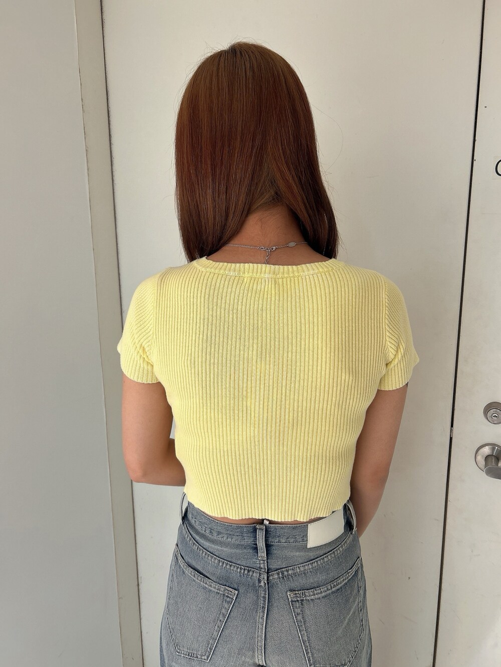 イエロー系のニット/セーター、ブルー系のデニムパンツ、ホワイト系のパンプスを着用したレディースの春コーディネートの5枚目の写真