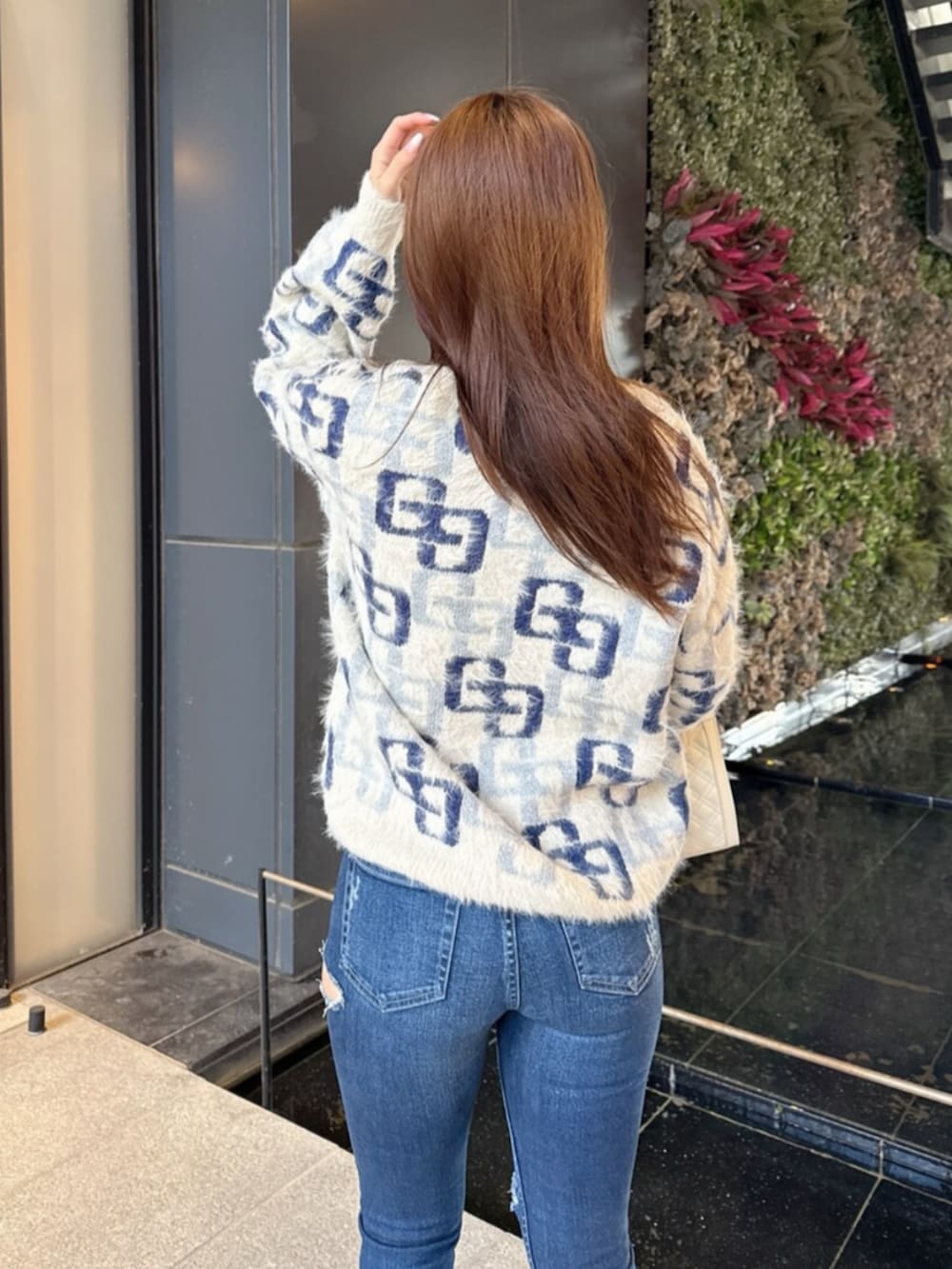 ブラック系のブーツ、ホワイト系のニット/セーター、ブルー系のデニムパンツを着用したレディースの冬コーディネートの6枚目の写真