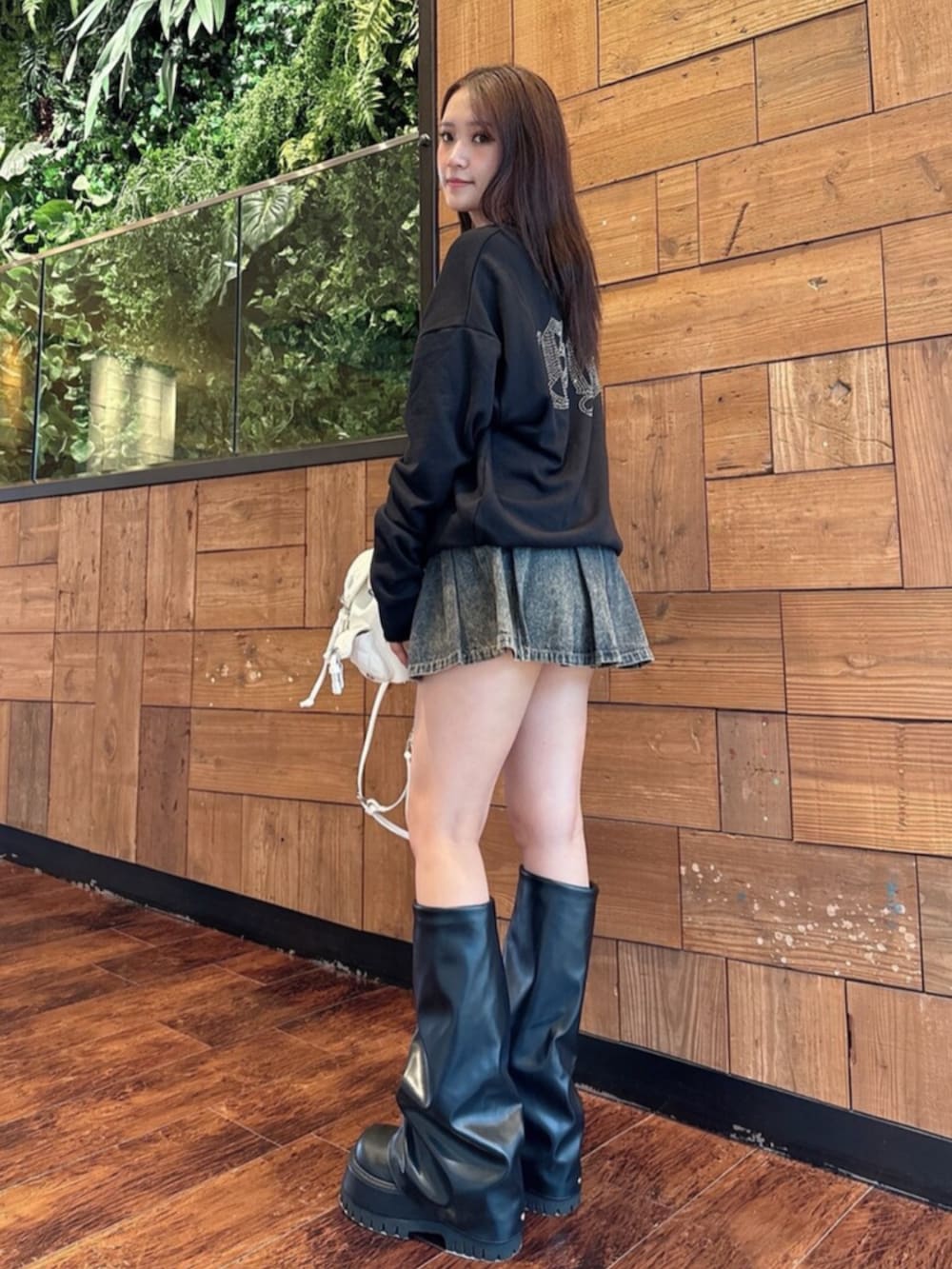 ブルー系のデニムスカート、ブラック系のブーツ、ブラック系のパーカーを着用したレディースの秋コーディネートの2枚目の写真