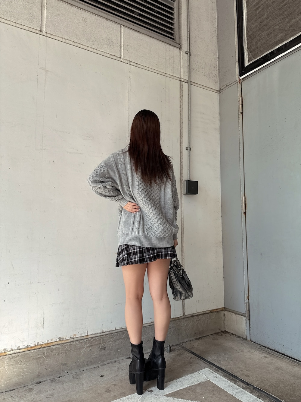 グレー系のニット/セーター、ブラック系のスカート、ブラック系のハンドバッグを着用したレディースの秋コーディネートの3枚目の写真