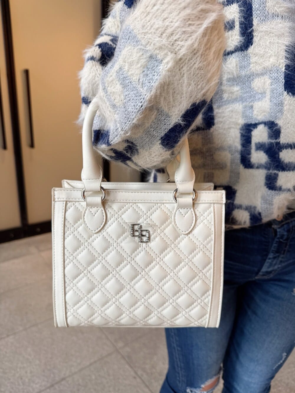 ブラック系のブーツ、ホワイト系のニット/セーター、ブルー系のデニムパンツを着用したレディースの冬コーディネートの7枚目の写真