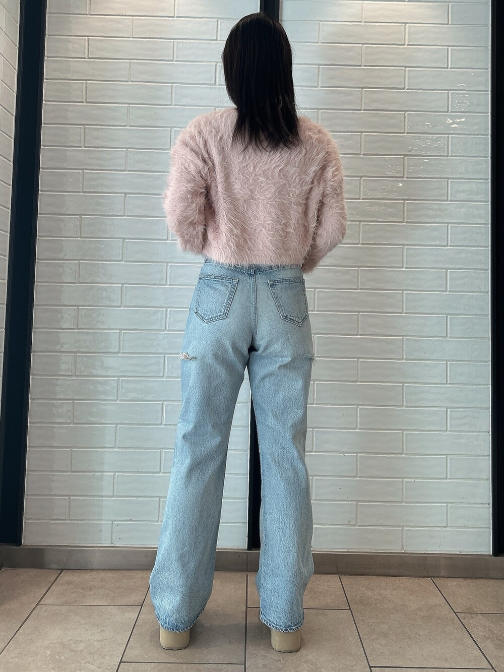 ピンク系のニット/セーター、ブルー系のデニムパンツ、ベージュ系のブーツを着用したレディースの冬コーディネートの3枚目の写真