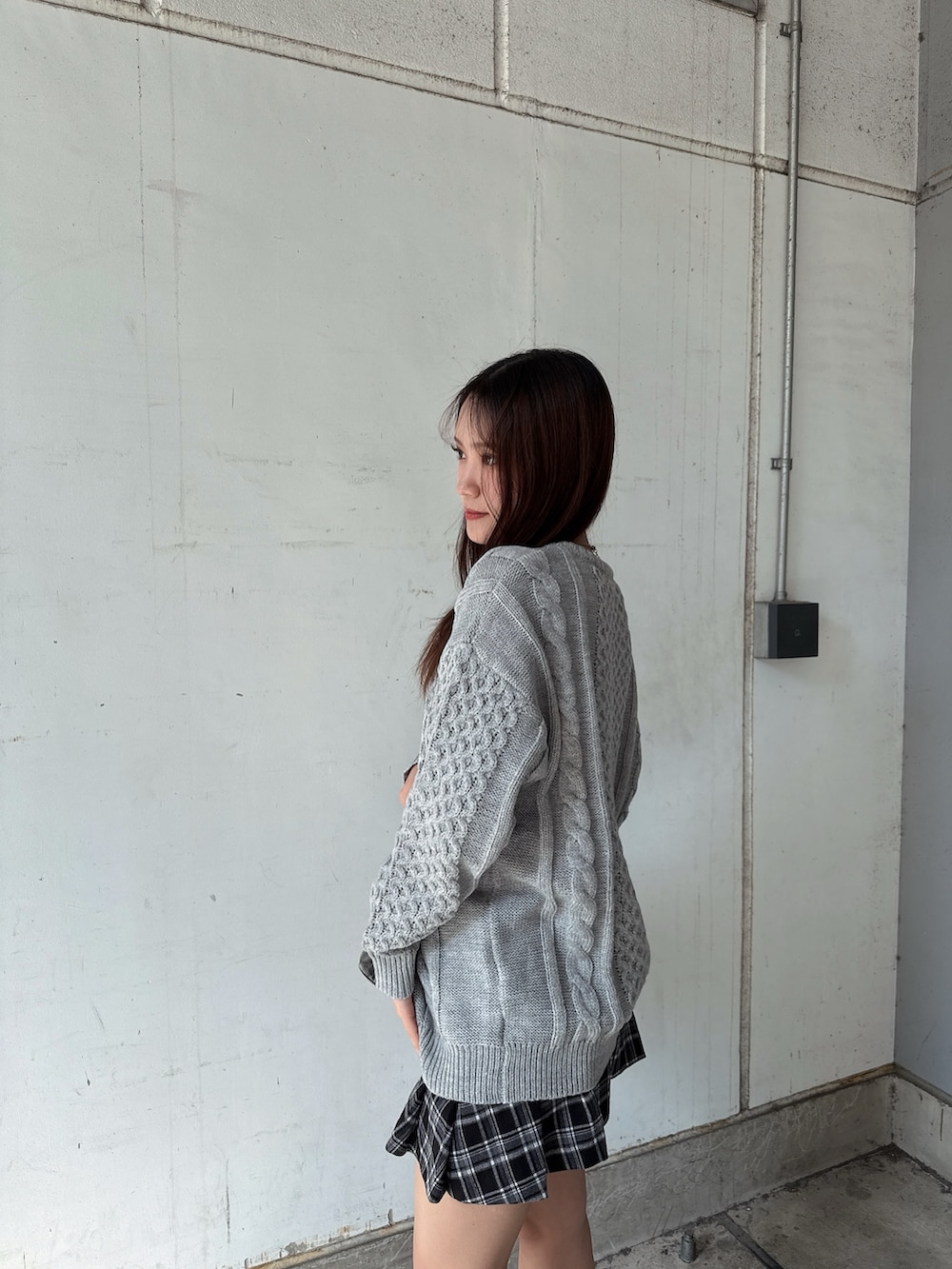 グレー系のニット/セーター、ブラック系のスカート、ブラック系のハンドバッグを着用したレディースの秋コーディネートの5枚目の写真