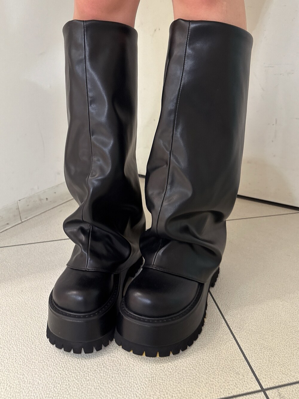 ブラック系のニット/セーター、ブラック系のスカート、ブラック系のブーツを着用したレディースの秋コーディネートの9枚目の写真