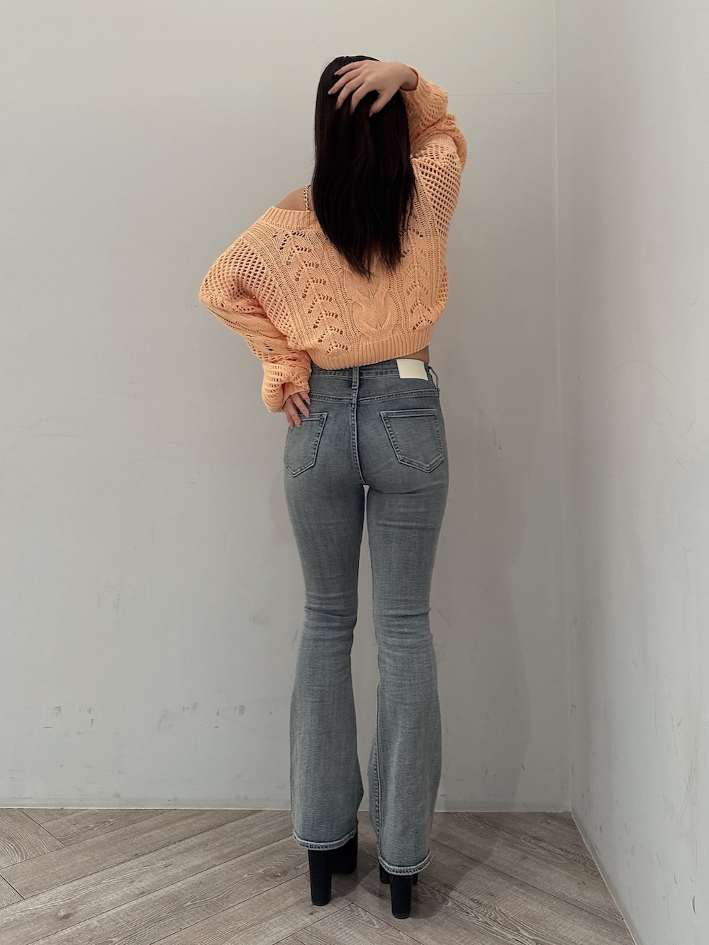 オレンジ系のニット/セーター、ホワイト系のキャミソール、ブルー系のデニムパンツを着用したレディースの春コーディネートの3枚目の写真