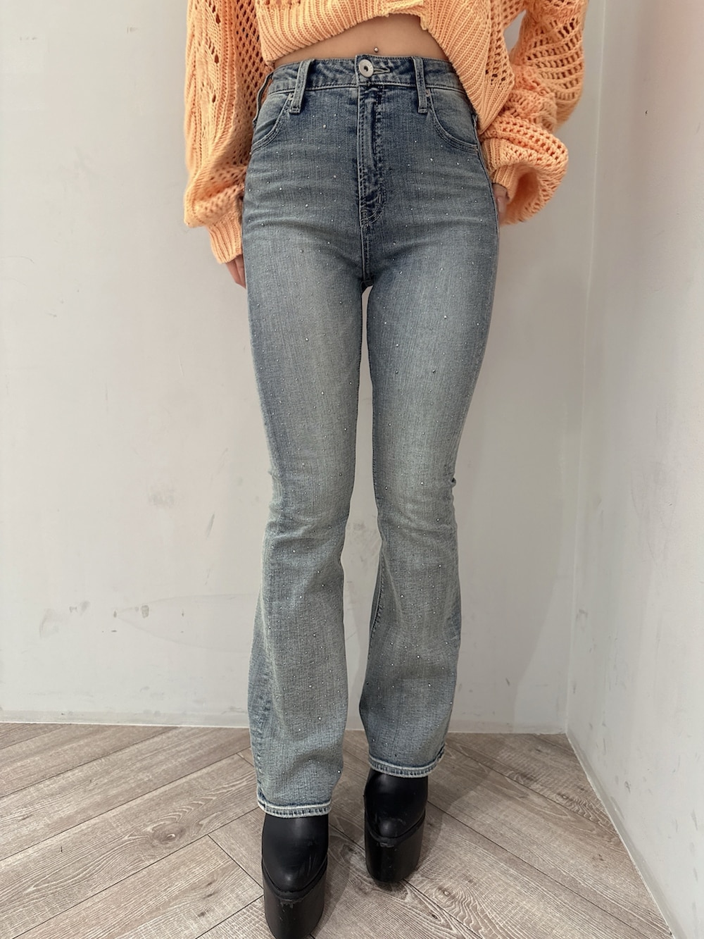 オレンジ系のニット/セーター、ホワイト系のキャミソール、ブルー系のデニムパンツを着用したレディースの春コーディネートの8枚目の写真