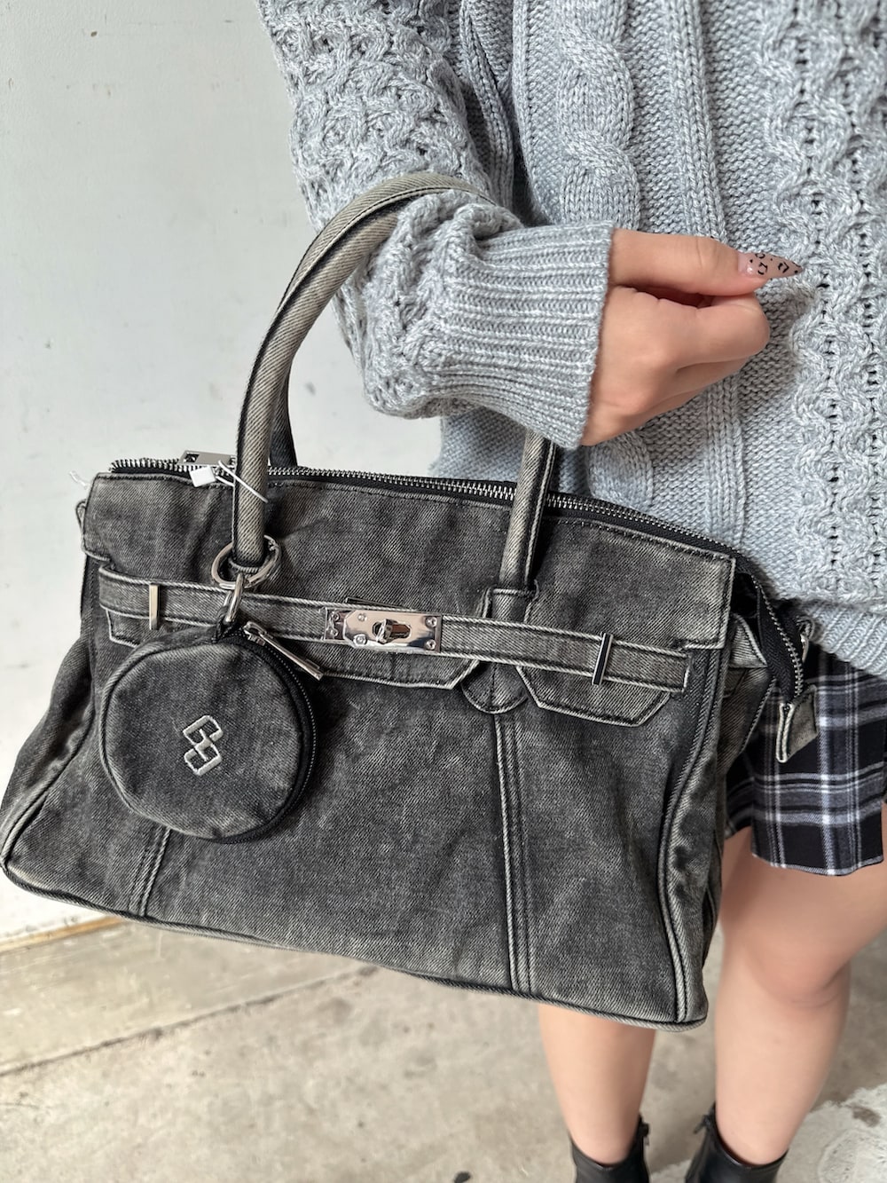 グレー系のニット/セーター、ブラック系のスカート、ブラック系のハンドバッグを着用したレディースの秋コーディネートの9枚目の写真