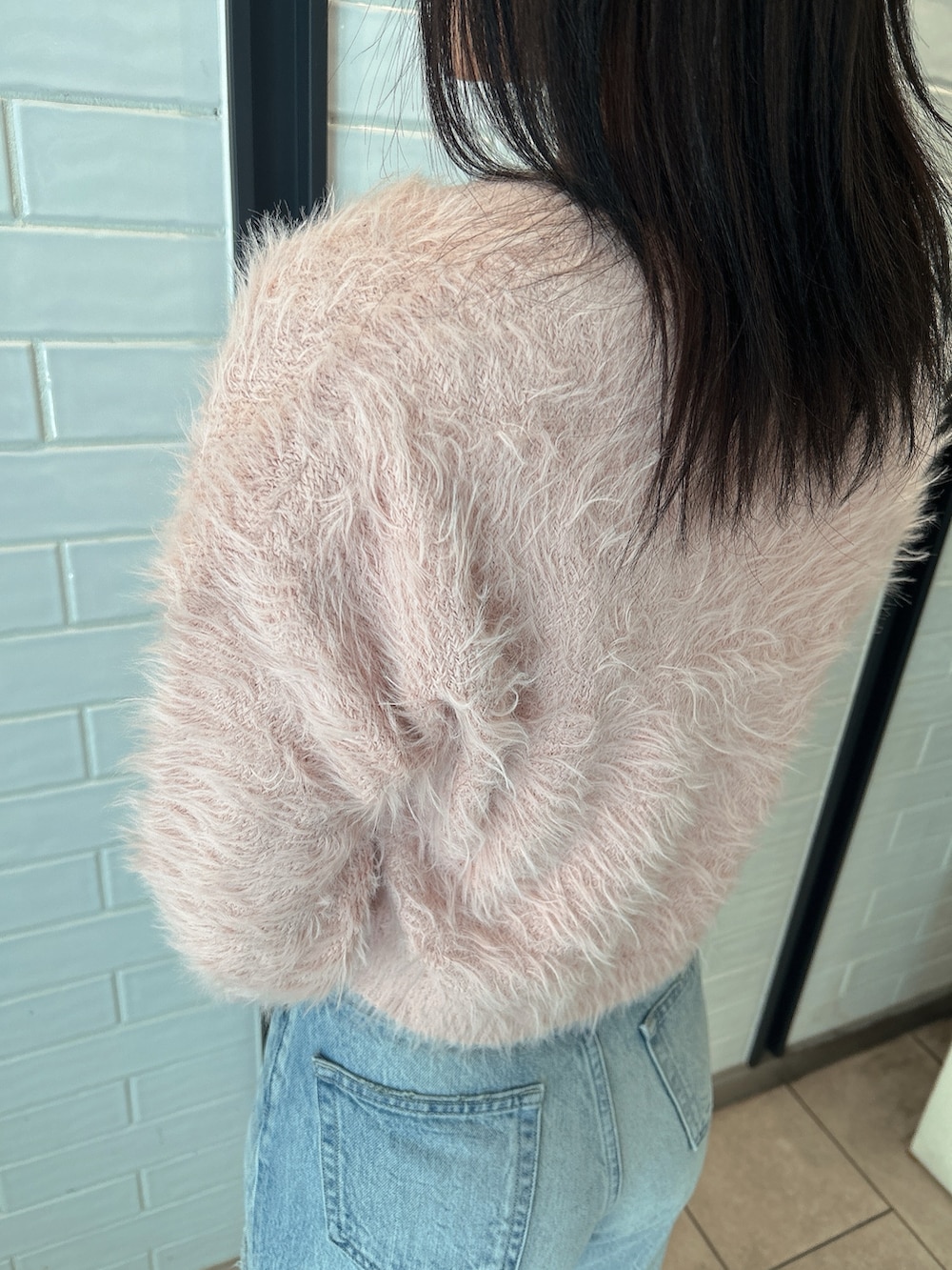 ピンク系のニット/セーター、ブルー系のデニムパンツ、ベージュ系のブーツを着用したレディースの冬コーディネートの6枚目の写真