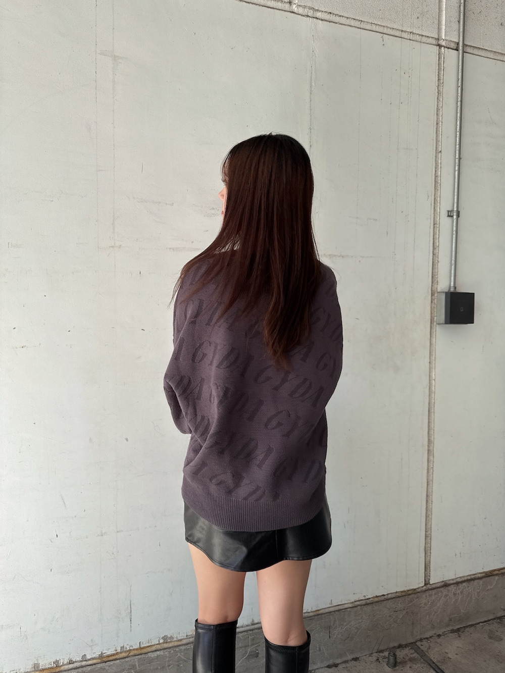 グレー系のニット/セーター、ブラック系のスカート、ブラック系のブーツを着用したレディースの秋コーディネートの6枚目の写真