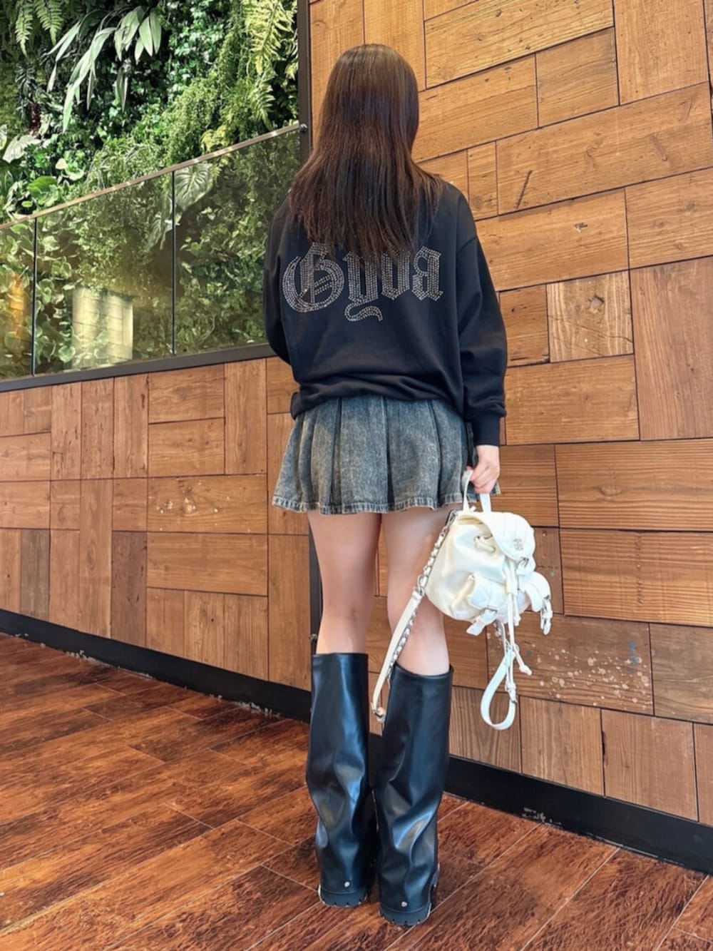 ブルー系のデニムスカート、ブラック系のブーツ、ブラック系のパーカーを着用したレディースの秋コーディネートの3枚目の写真