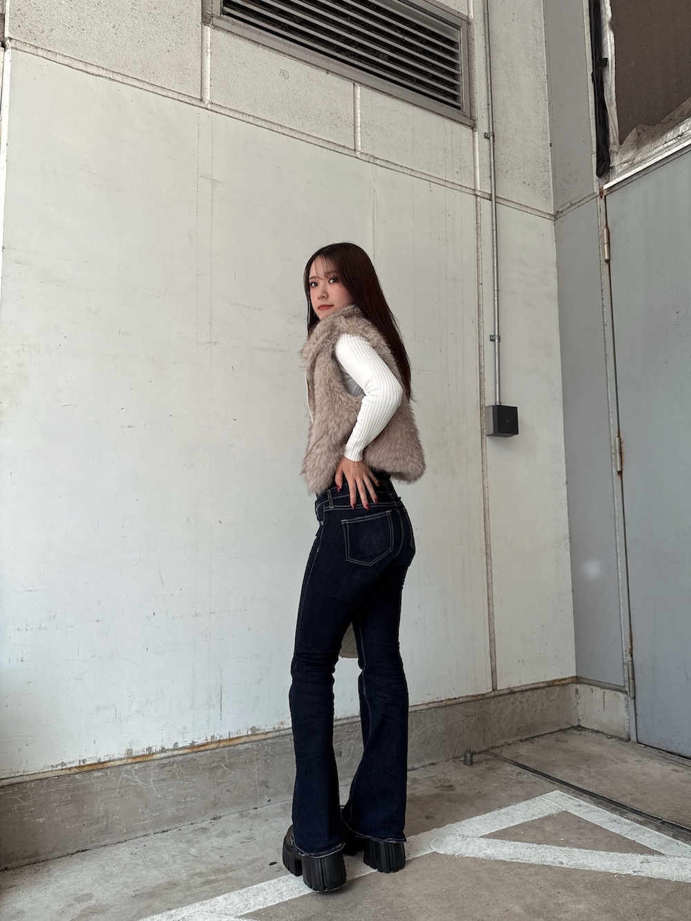 ホワイト系のニット/セーター、ホワイト系のベスト、ブルー系のデニムパンツを着用したレディースの秋コーディネートの2枚目の写真