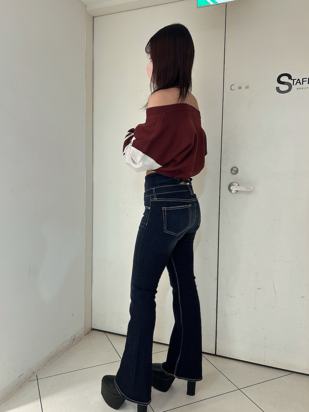 ブルー系のデニムパンツ、レッド系のニット/セーター、ブラック系のブーツを着用したレディースの秋コーディネートの5枚目の写真