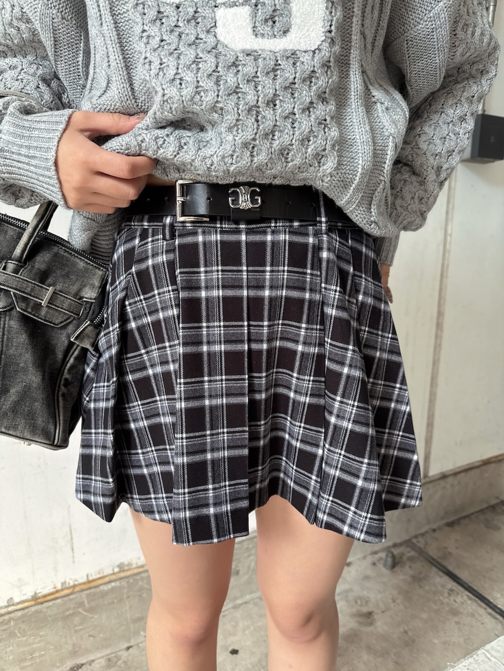 グレー系のニット/セーター、ブラック系のスカート、ブラック系のハンドバッグを着用したレディースの秋コーディネートの8枚目の写真