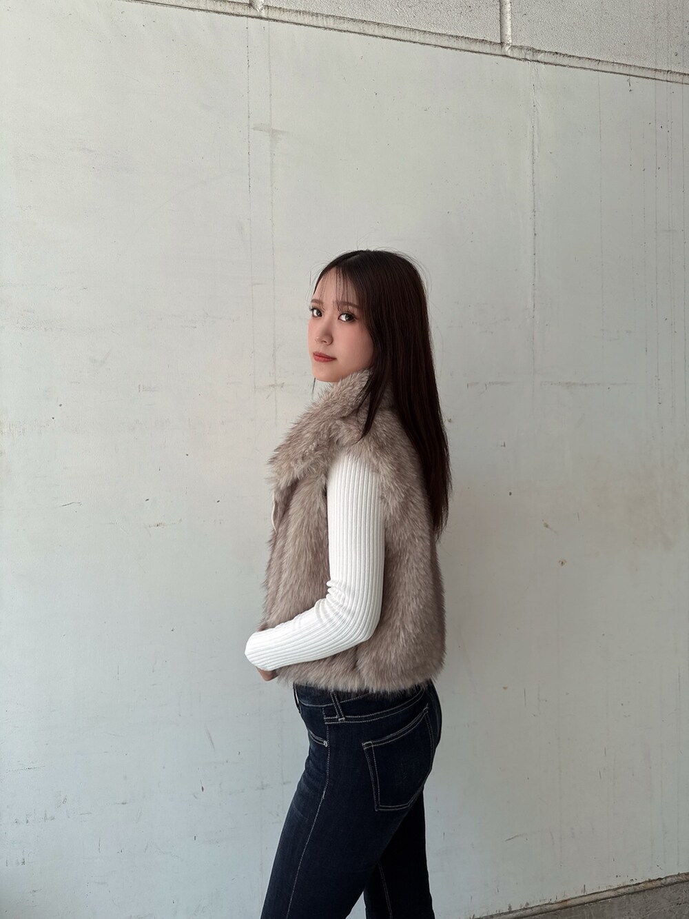 ホワイト系のニット/セーター、ホワイト系のベスト、ブルー系のデニムパンツを着用したレディースの秋コーディネートの5枚目の写真