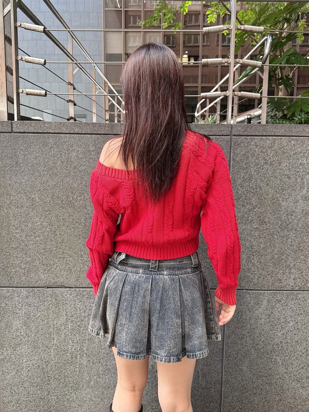 レッド系のニット/セーター、ブルー系のデニムスカート、ブラック系のブーツを着用したレディースの秋コーディネートの6枚目の写真