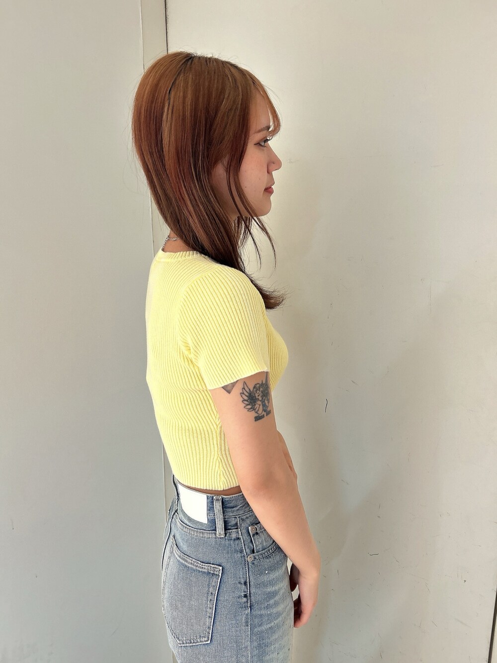 イエロー系のニット/セーター、ブルー系のデニムパンツ、ホワイト系のパンプスを着用したレディースの春コーディネートの6枚目の写真