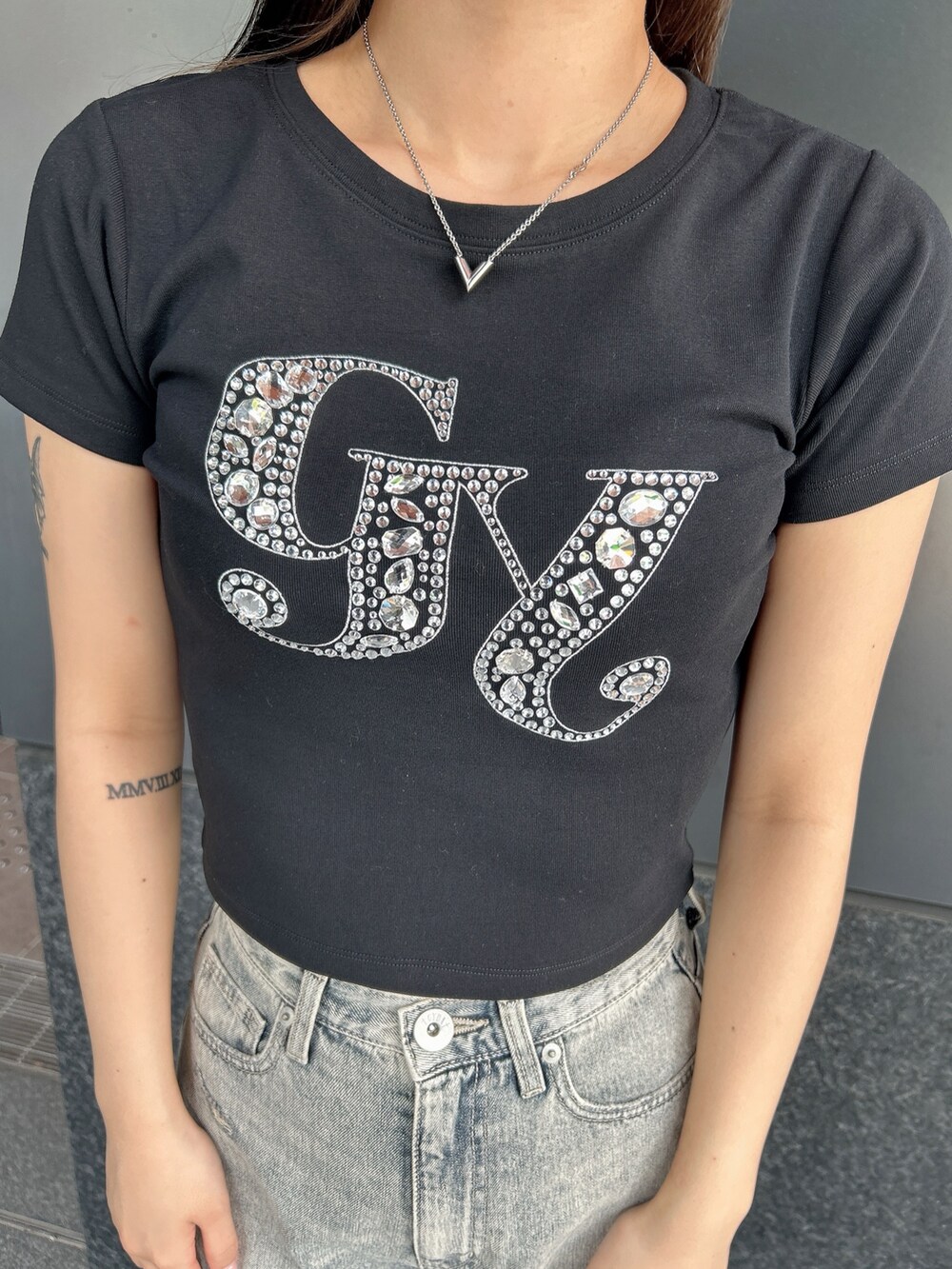 ブラック系のTシャツ/カットソー、ブルー系のデニムパンツ、ブラック系のサンダルを着用したレディースの夏コーディネートの7枚目の写真