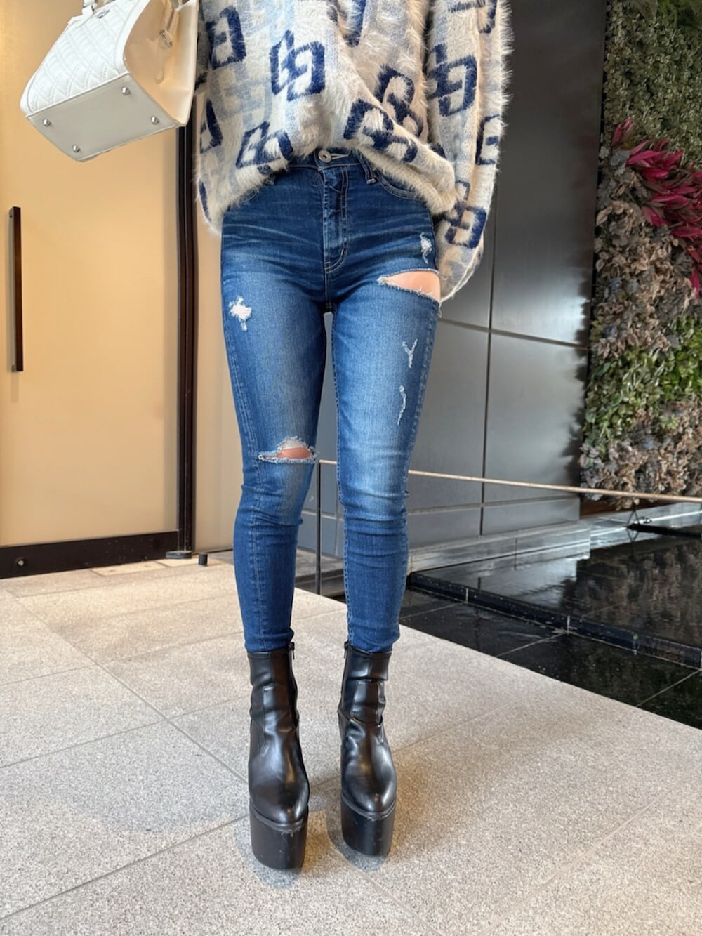 ブラック系のブーツ、ホワイト系のニット/セーター、ブルー系のデニムパンツを着用したレディースの冬コーディネートの8枚目の写真