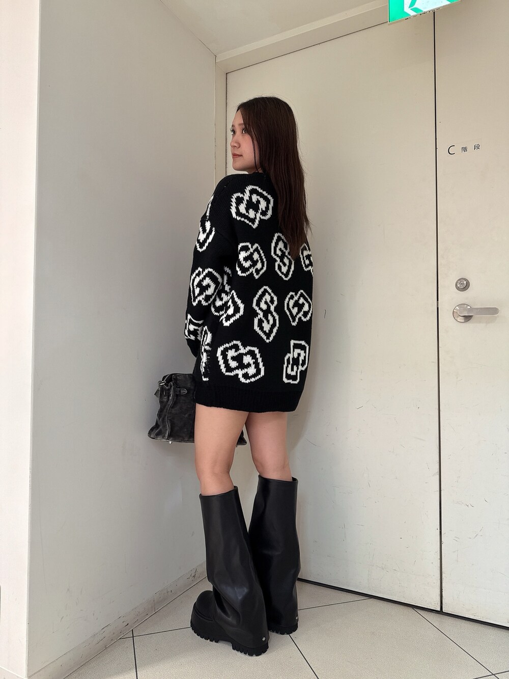 ブラック系のニット/セーター、ブラック系のスカート、ブラック系のブーツを着用したレディースの秋コーディネートの2枚目の写真