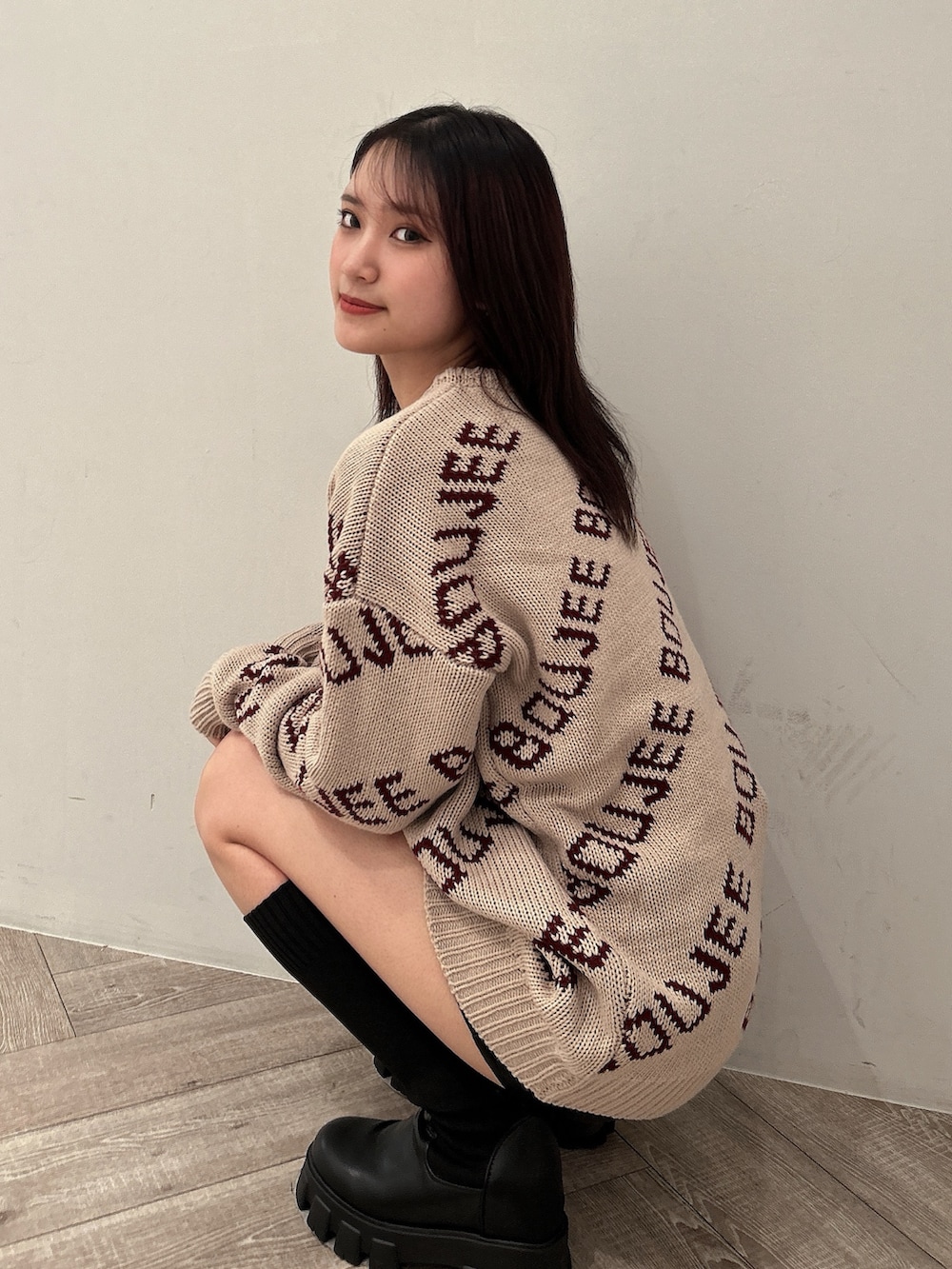 ベージュ系のニット/セーター、ブラック系のスカート、ブラック系のブーツを着用したレディースの秋コーディネートの6枚目の写真