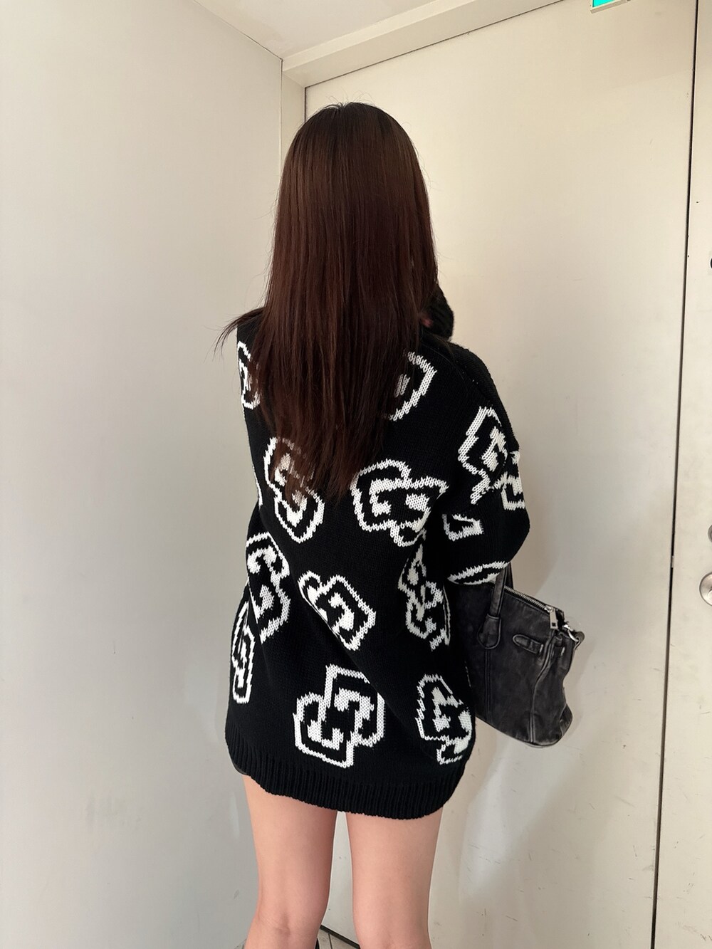 ブラック系のニット/セーター、ブラック系のスカート、ブラック系のブーツを着用したレディースの秋コーディネートの6枚目の写真