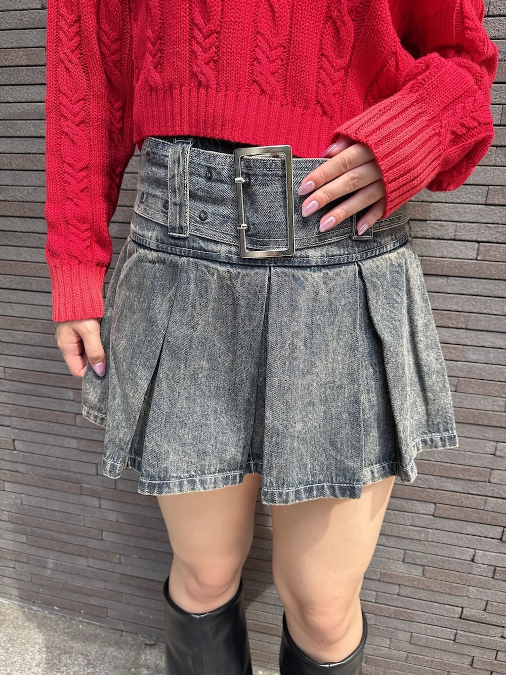 レッド系のニット/セーター、ブルー系のデニムスカート、ブラック系のブーツを着用したレディースの秋コーディネートの8枚目の写真