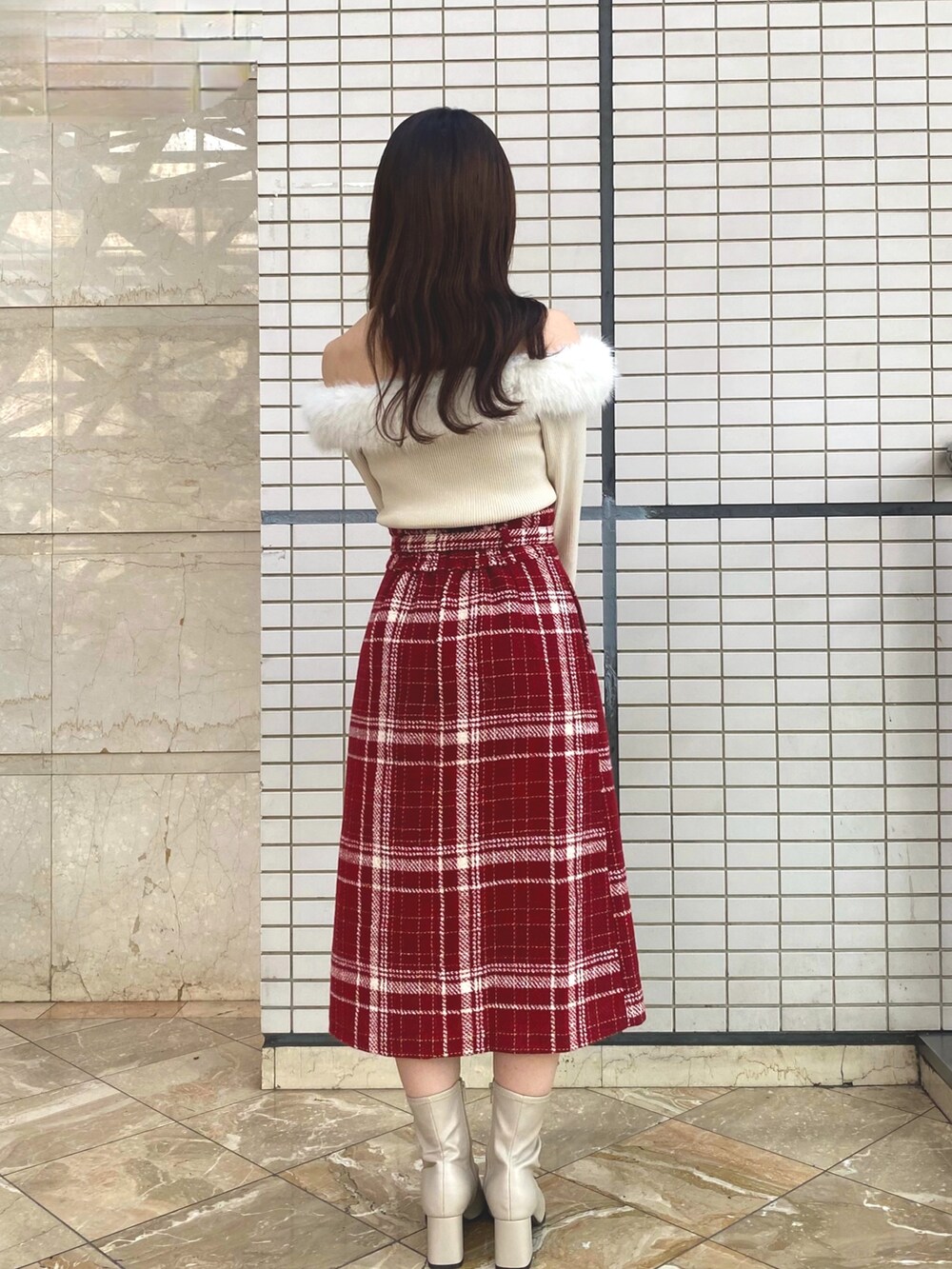 ベージュ系のニット/セーター、レッド系のスカート、ベージュ系のブーツを着用したレディースの秋コーディネートの3枚目の写真