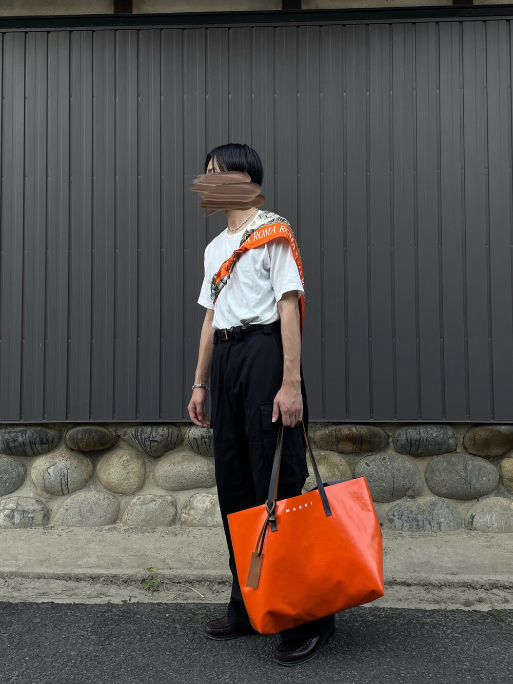 ブラック系のパンツ、オレンジ系のバッグ、ブラウン系のローファーを着用したメンズの夏コーディネートの2枚目の写真