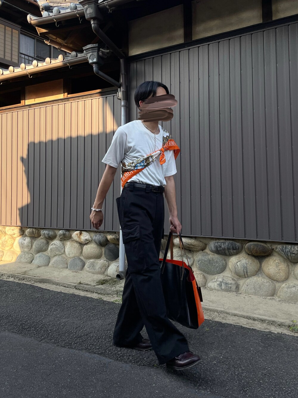 ブラック系のパンツ、オレンジ系のバッグ、ブラウン系のローファーを着用したメンズの夏コーディネートの3枚目の写真