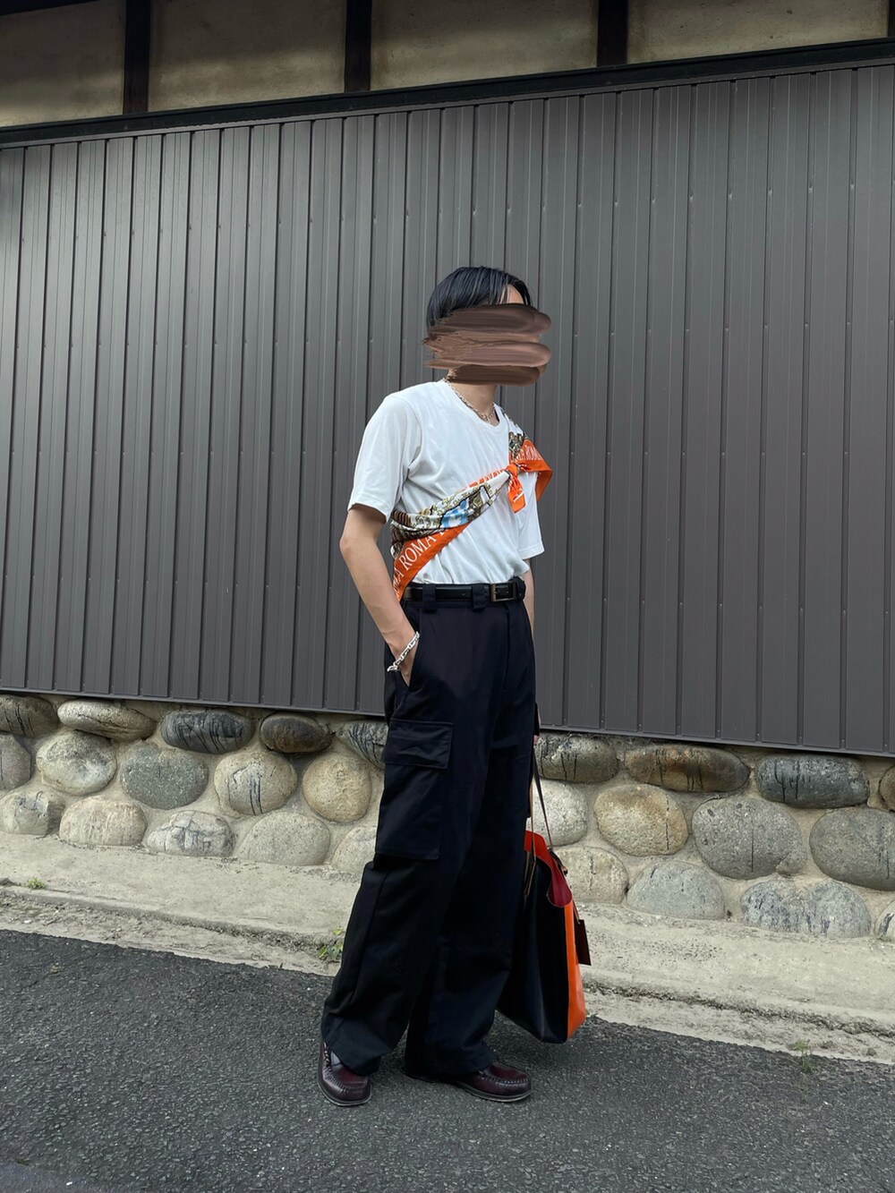 ブラック系のパンツ、オレンジ系のバッグ、ブラウン系のローファーを着用したメンズの夏コーディネートの4枚目の写真