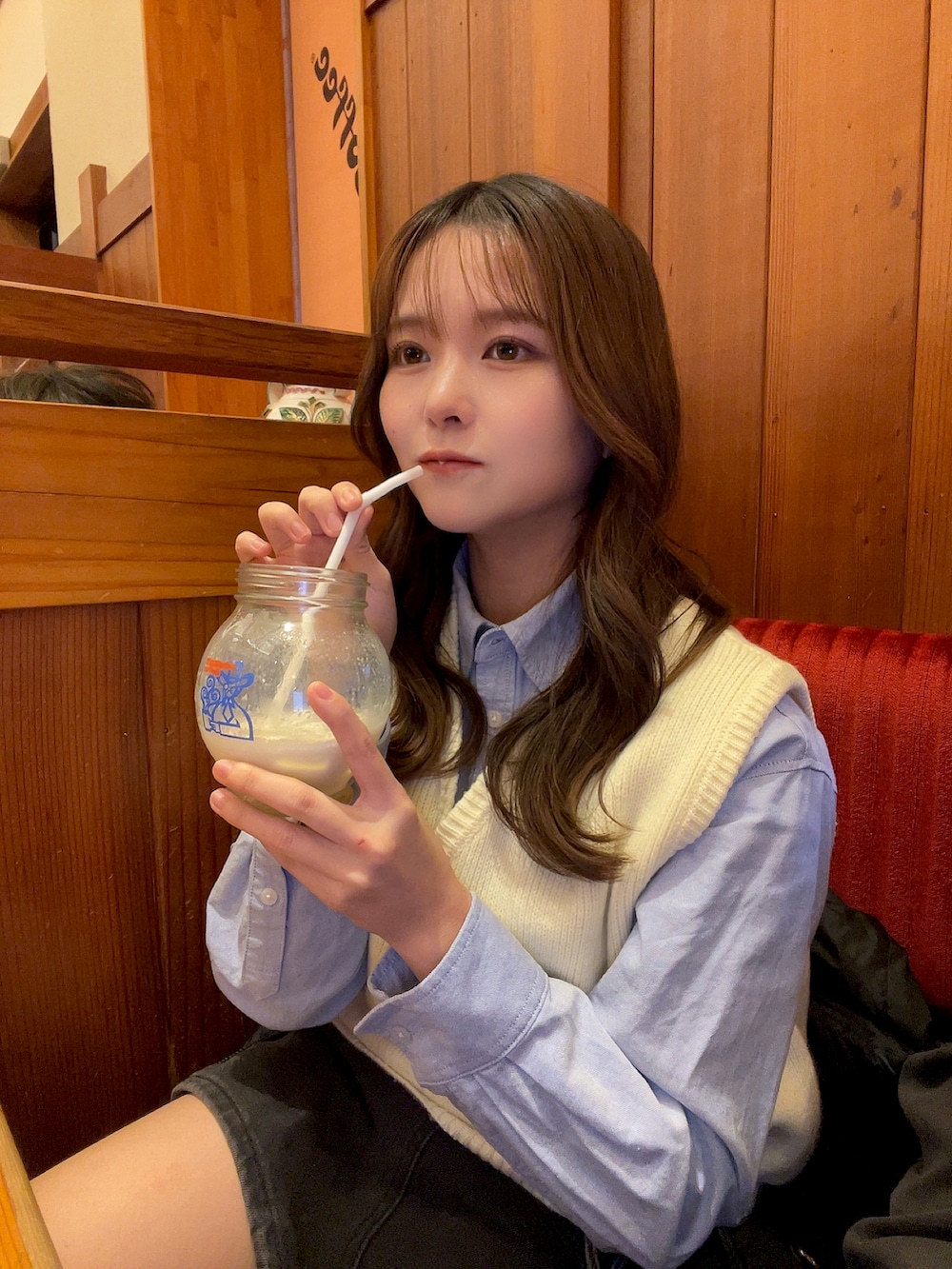 ホワイト系のベスト、グレー系のデニムスカートを着用したレディースの冬コーディネートの3枚目の写真