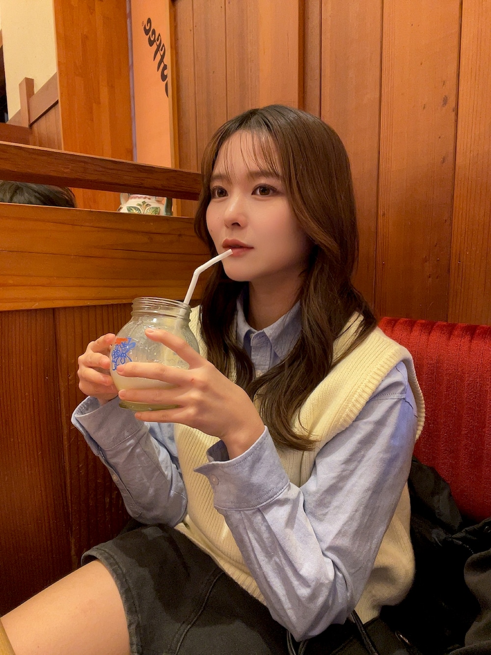 ホワイト系のベスト、グレー系のデニムスカートを着用したレディースの冬コーディネートの2枚目の写真