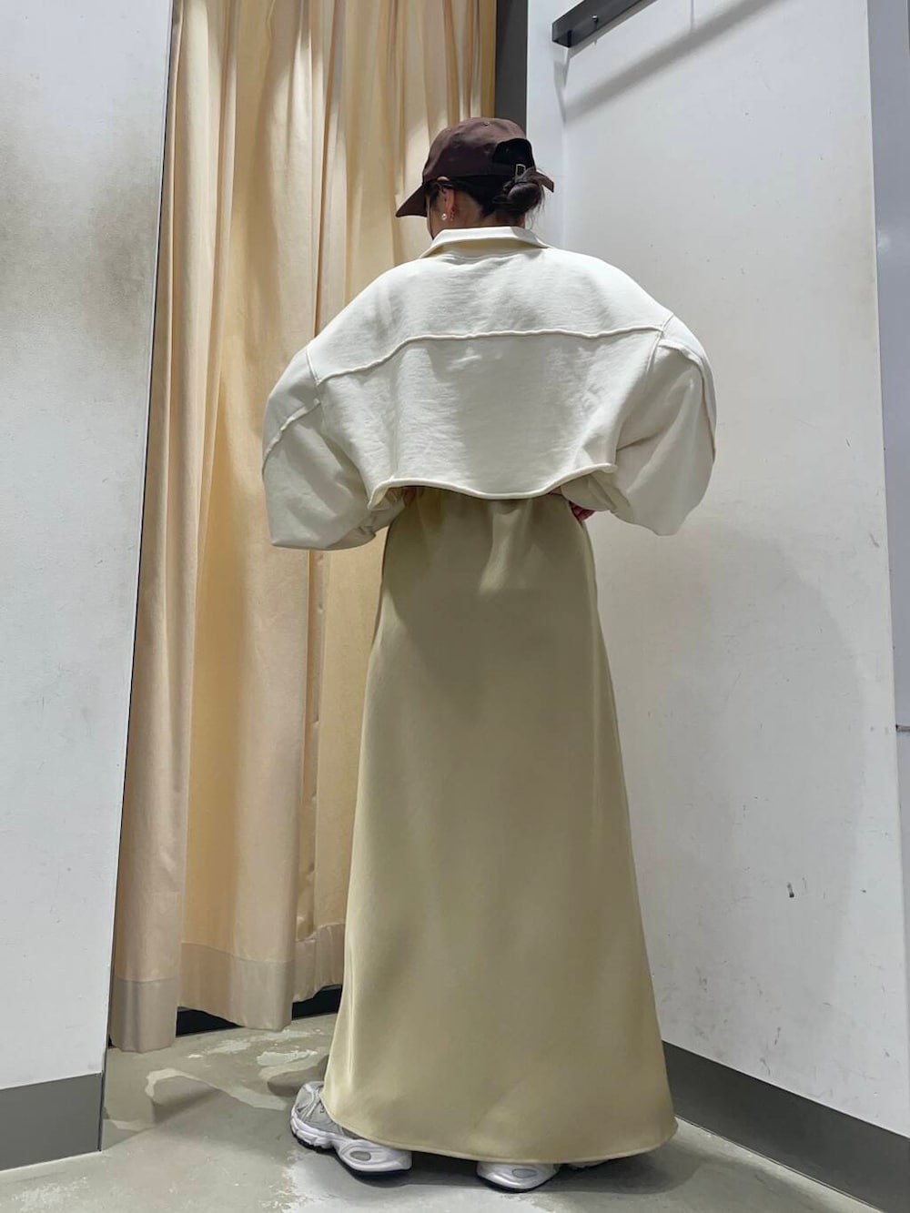 ホワイト系のスウェット、ベージュ系のスカート、ブラウン系のキャップを着用したレディースの冬コーディネートの2枚目の写真