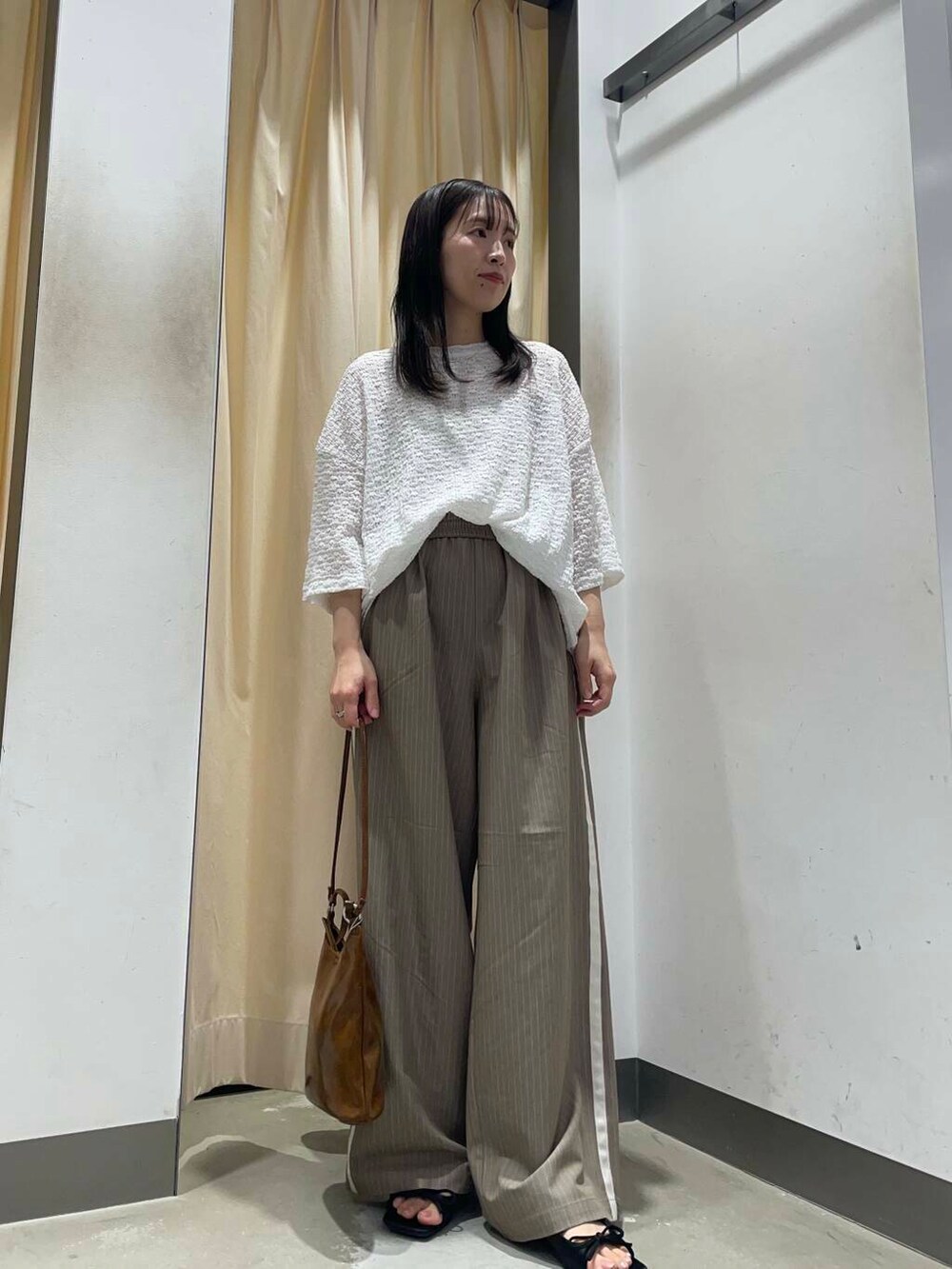 ブラウン系のショルダーバッグ、ホワイト系のTシャツ/カットソーを着用したレディースの春コーディネートの2枚目の写真